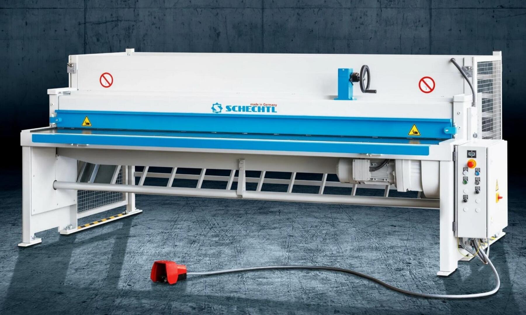 Eine große industrielle Blechschneidemaschine mit blauen und weißen Platten, beschriftet mit Schechtl, steht auf einem Betonboden. Ein rotes Fußpedal ist mit einem Kabel verbunden, und an der rechten Seite sind Steuertasten angebracht.