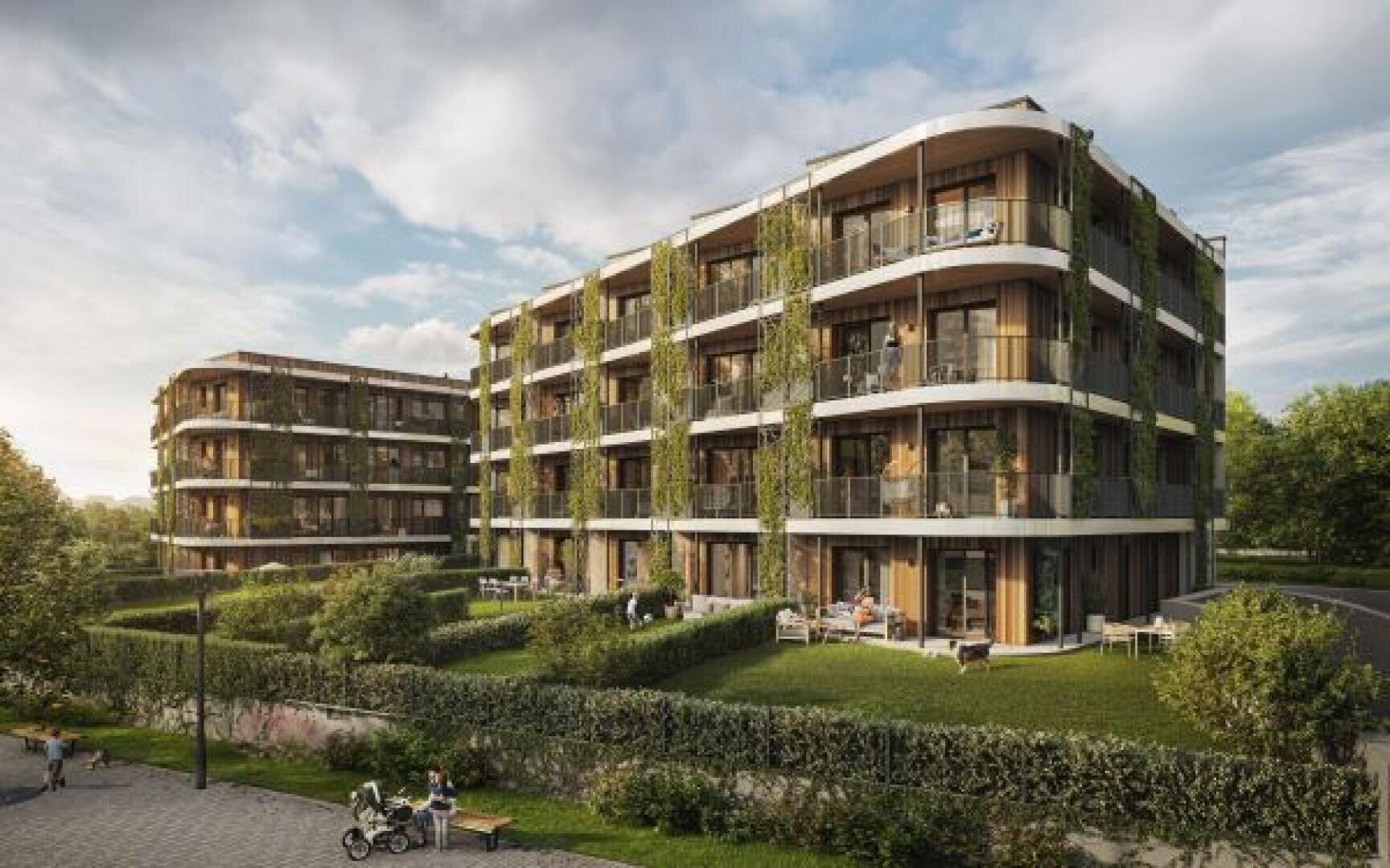 Modern four-storey residential buildings with curved balconies, large windows and lots of greenery. Residents relax on balconies and terraces, surrounded by manicured lawns and hedges under a partly cloudy sky.