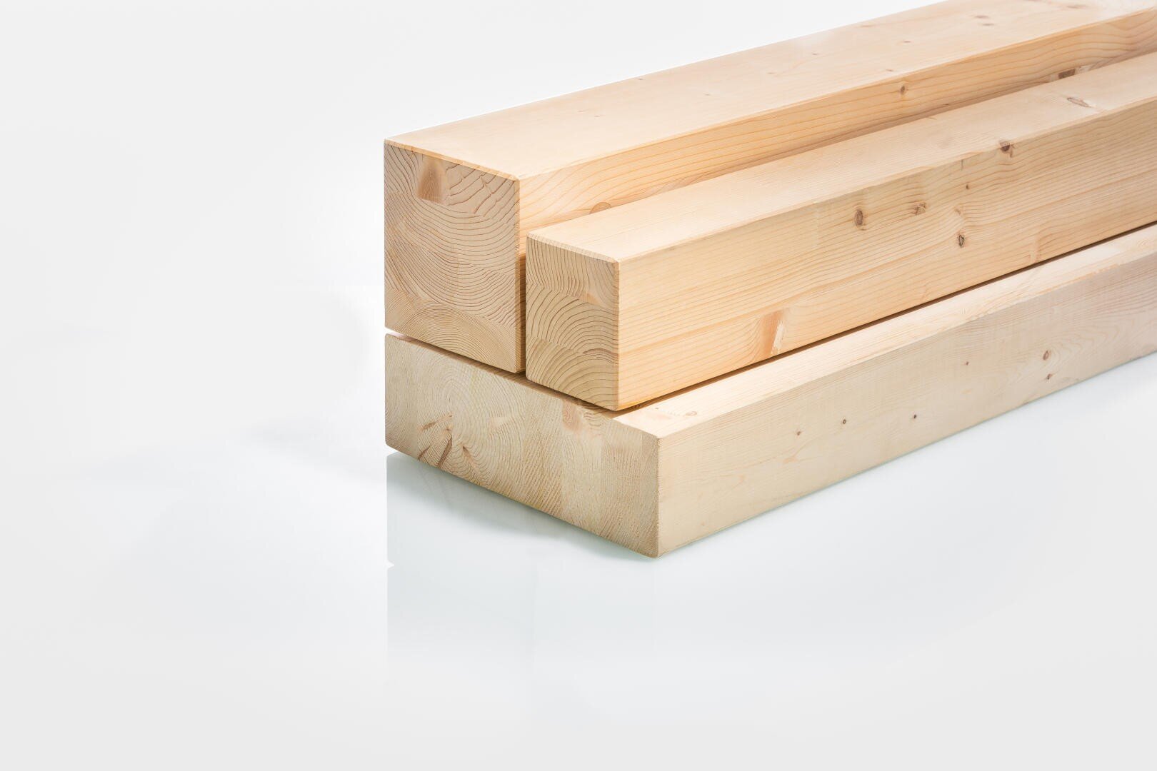 Drei helle Holzbalken, gestapelt auf einer weißen Fläche, mit sichtbarer Holzmaserung und glatten, sauberen Kanten.