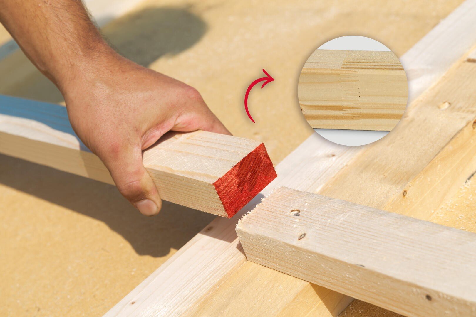 A hand holds a piece of wood with a red painted end and aligns it with a wooden frame. A close-up shows a precise wooden joint, highlighted by a red arrow.