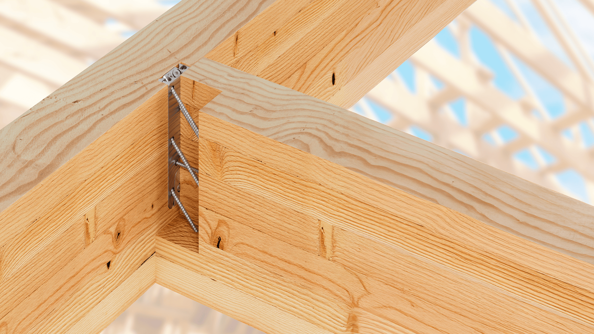 Close-up of wooden beams joined together with metal fasteners at a construction site, with a blurred background of other wooden framework and blue sky.