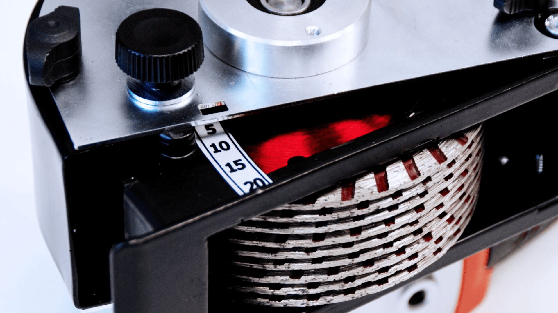 Nahaufnahme eines mechanischen Geräts mit einem Ziffernblatt (0–20), einem rot-weißen Spiralband und verschiedenen Metall- und Kunststoffknöpfen auf weißem Hintergrund.