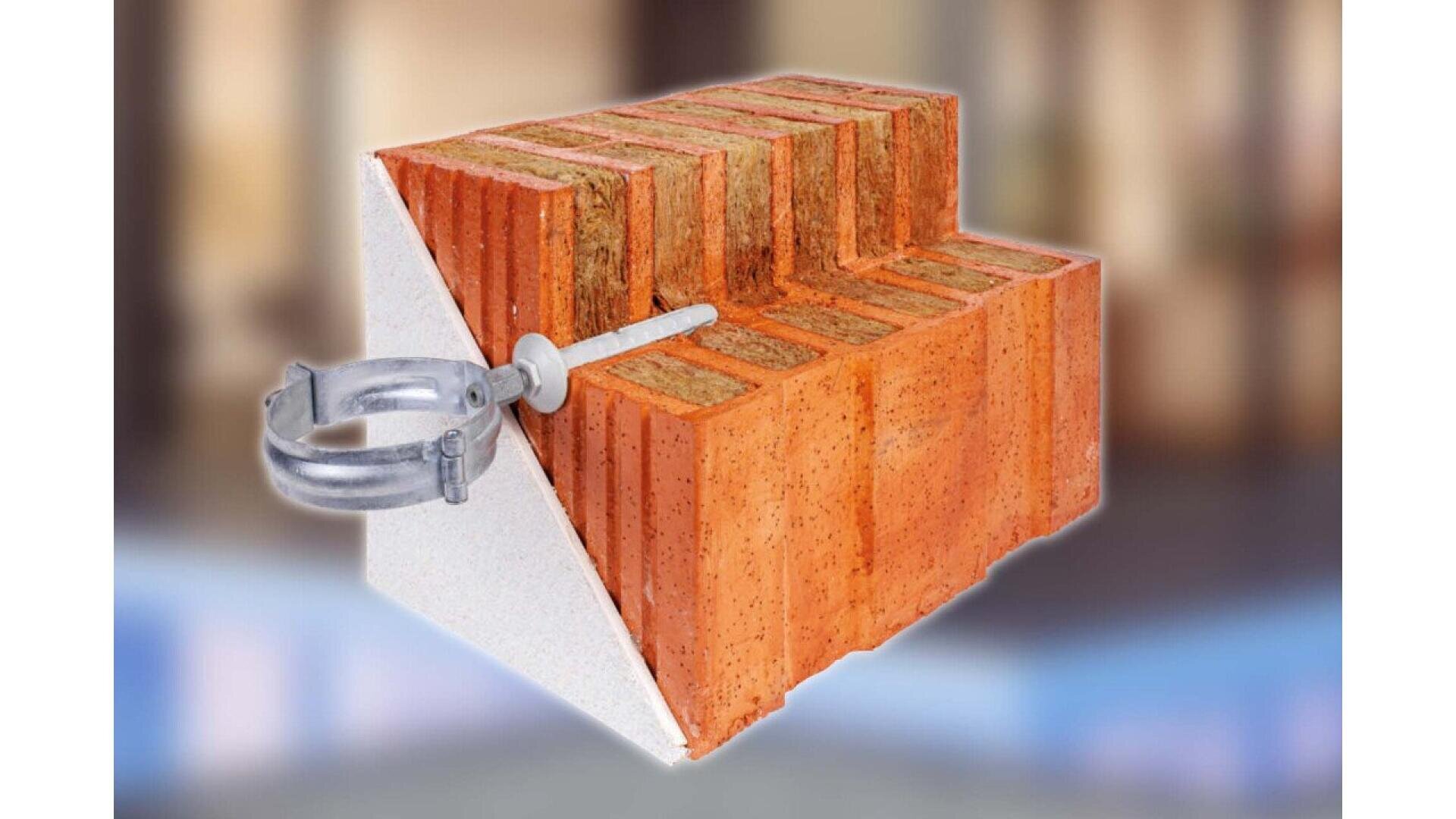 A cross-section of a brick wall with insulation, showing a metal wall tie and screw inserted through the insulation into the brick, demonstrating how the components are assembled. The background is blurred.