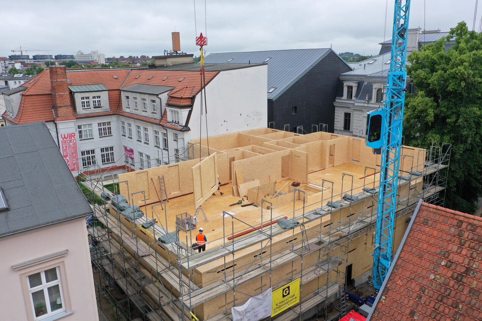 Eine Baustelle zeigt ein mehrstöckiges Gebäude, das mit MAgnumboard OSB gebaut wird. Die Baustelle ist in einer engen Straße einer Altstadt.
