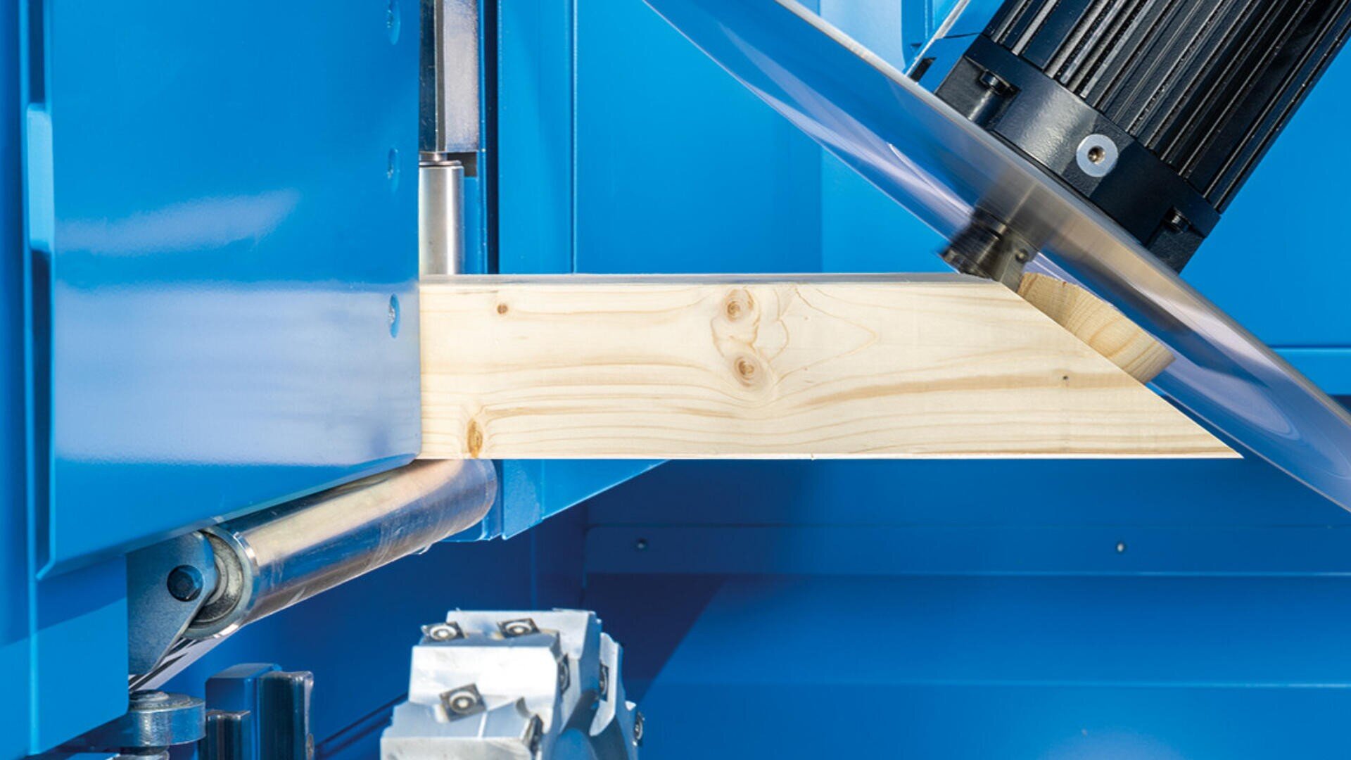 In einer blauen Industriemaschine schneidet ein Kreissägeblatt durch ein helles Holzbrett und veranschaulicht so den Holzbearbeitungsprozess.