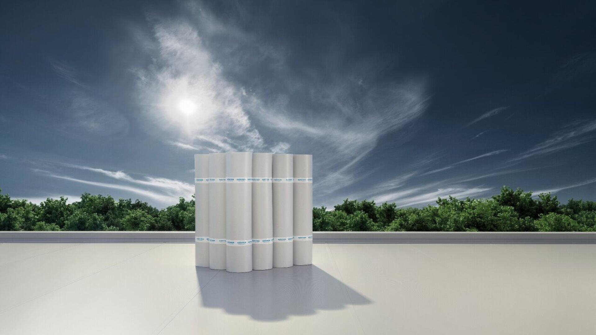 A group of white cylindrical rolls stands on a flat, light-colored surface outdoors, with green trees and a cloudy sky in the background. The sun is shining brightly above the horizon.