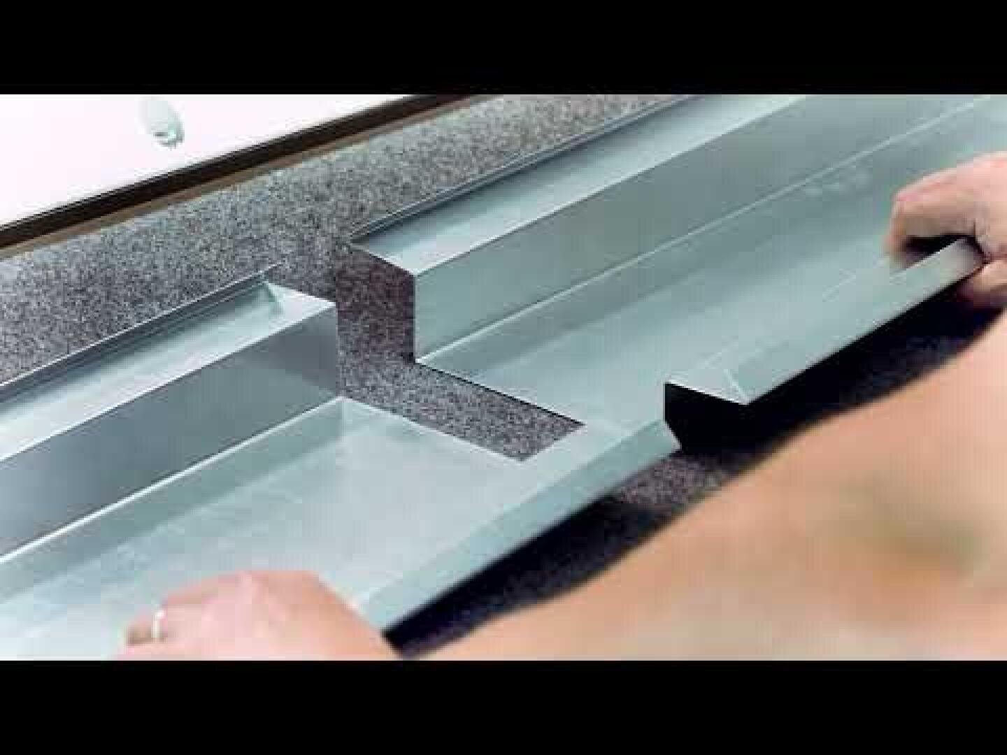 Zwei Hände halten zwei Metallteile mit ineinander greifenden Kerben, die auf einer grauen Fläche platziert sind, und fügen sie zusammen, um zu veranschaulichen, wie die Teile miteinander verbunden werden.