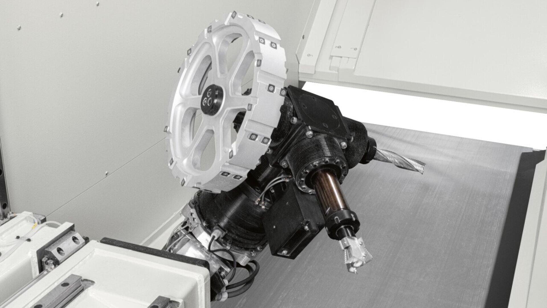 A close-up of a CNC machine tool with a rotating mechanism and attached cutting tool, positioned inside a clean, industrial enclosure.