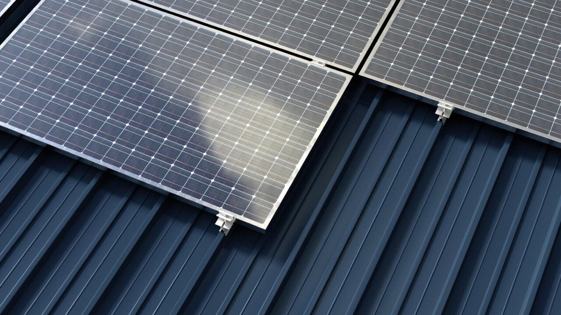 Close-up of solar panels mounted on a dark blue corrugated metal roof; sunlight and partially cloudy reflection visible on the panels.